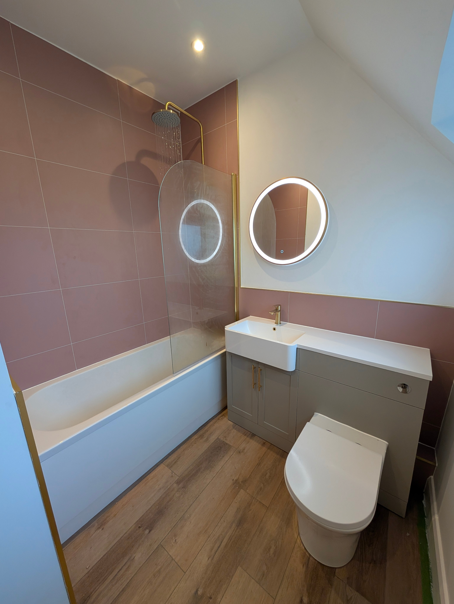 Pink-tiled bathroom with bath and brass fittings