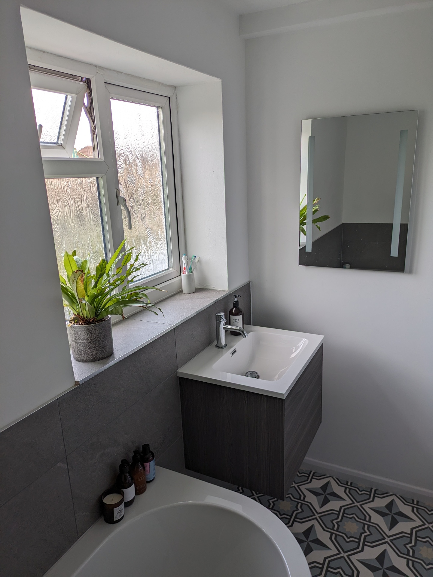 Modern bathroom vanity with wall-hung sink and grey tiling