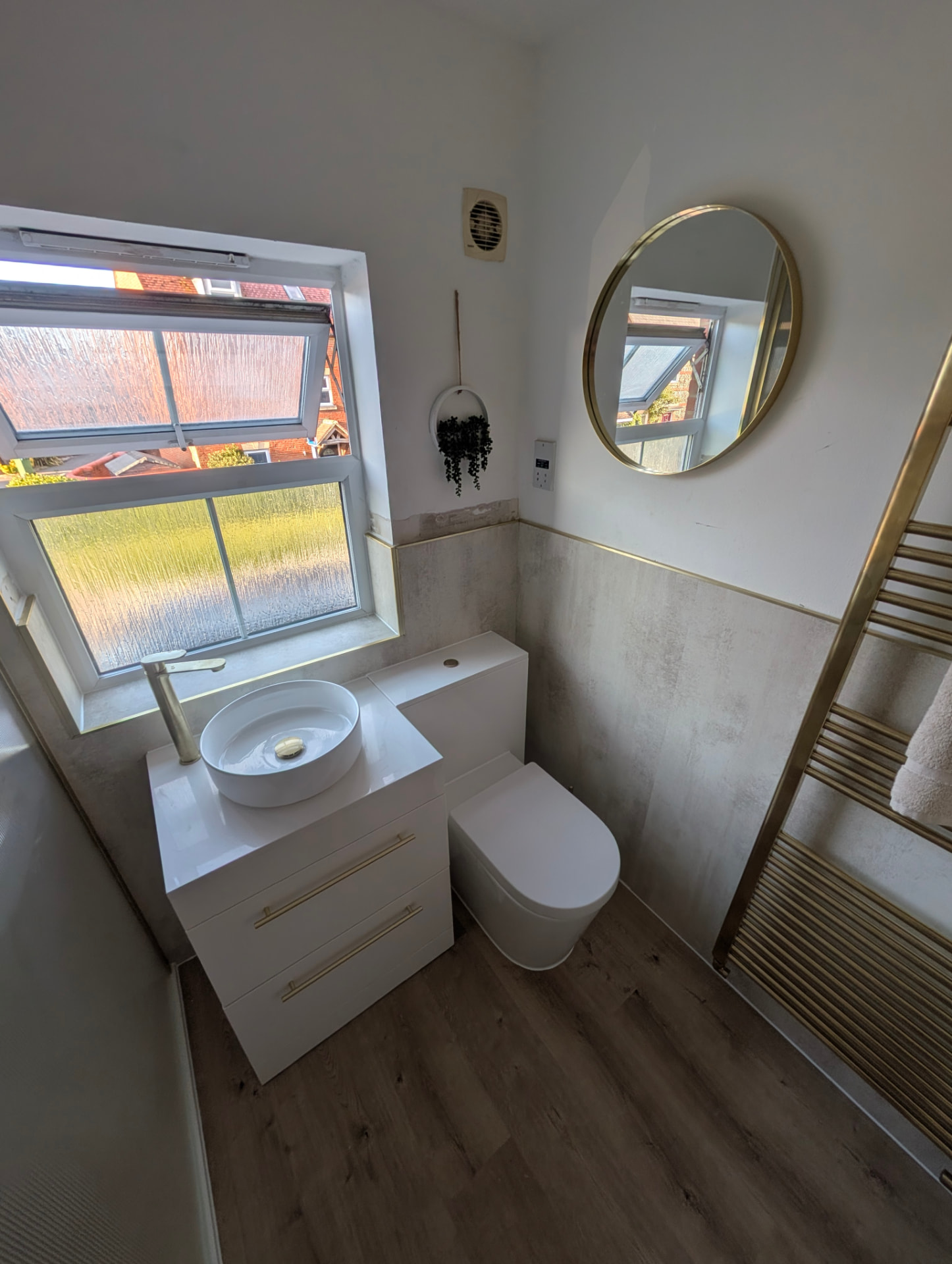 Worthing bathroom installation with countertop basin, round mirror and gold radiator Worthing bathroom installation with countertop basin, round mirror and gold radiator