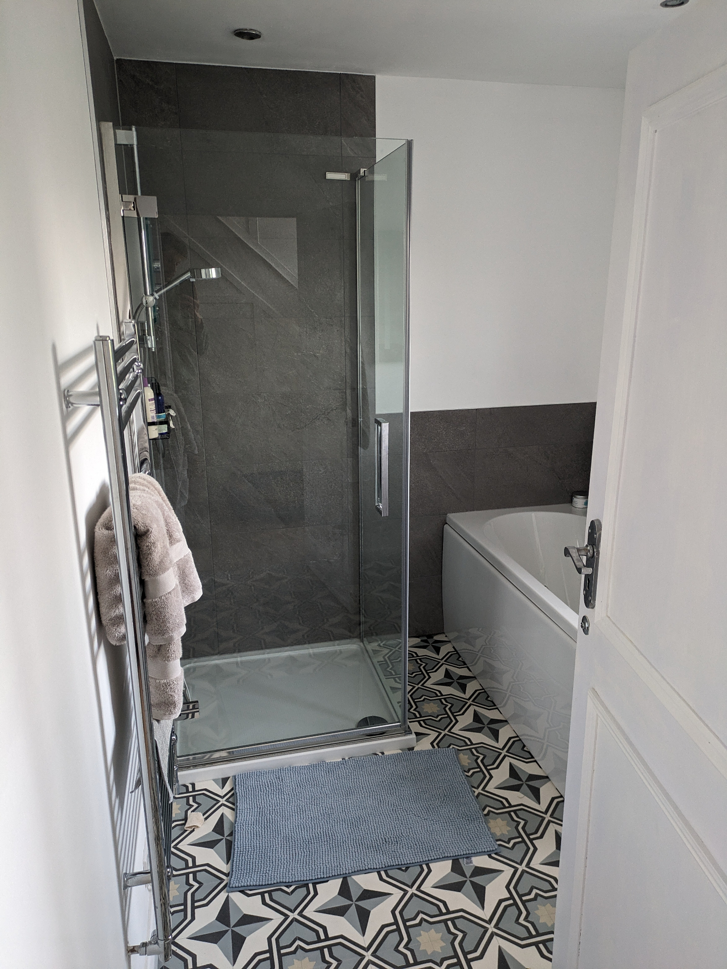 Completed bathroom installation with walk-in shower and patterned floor tiles