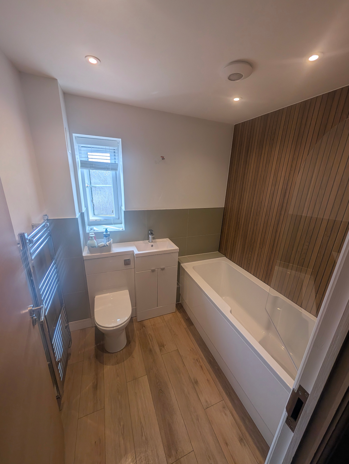 Bathroom with bath, vanity unit and slatted wood feature wall